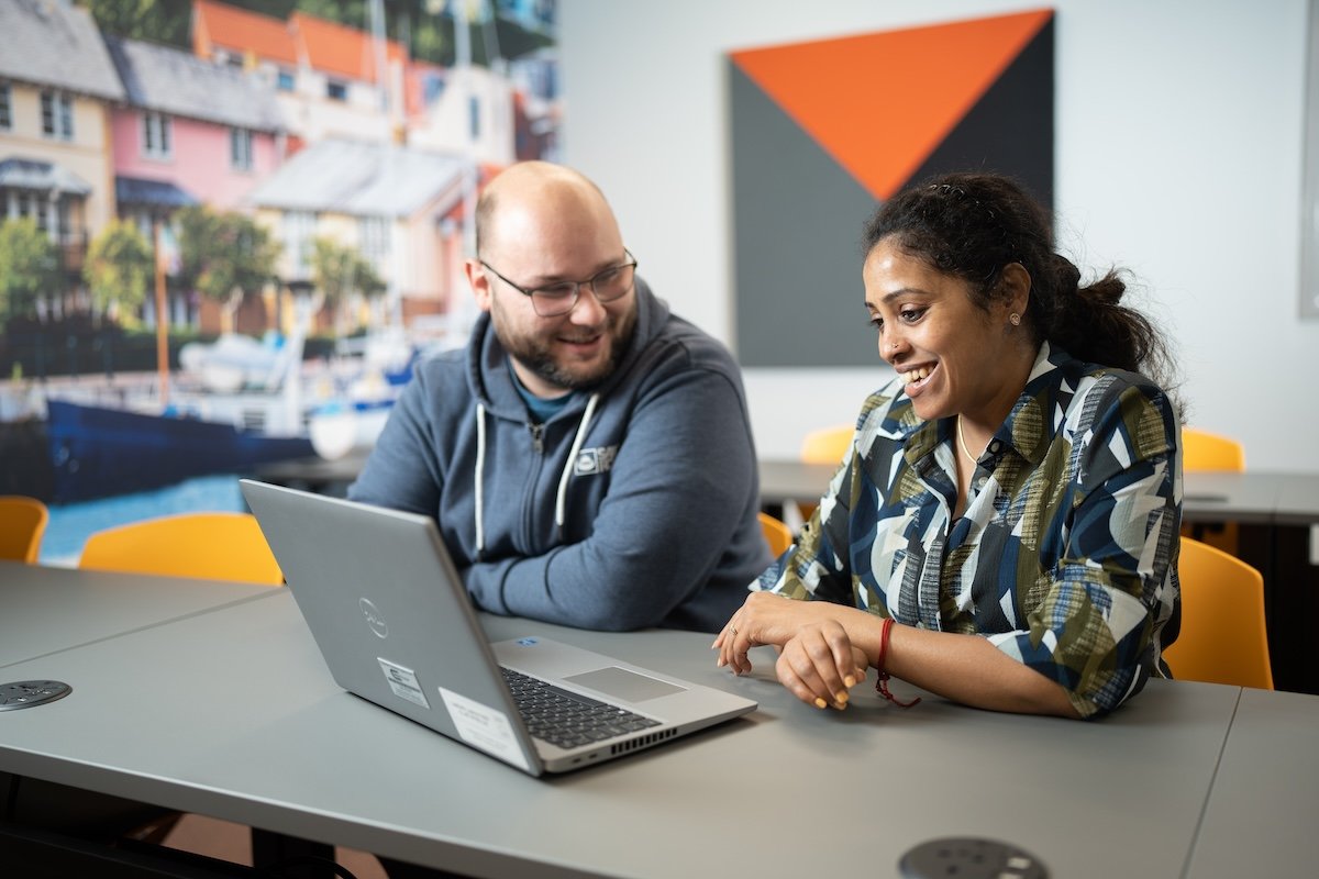 student and teacher look at a laptop