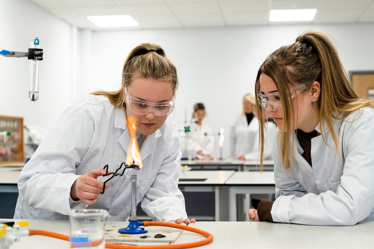 two females using a bunsen burner